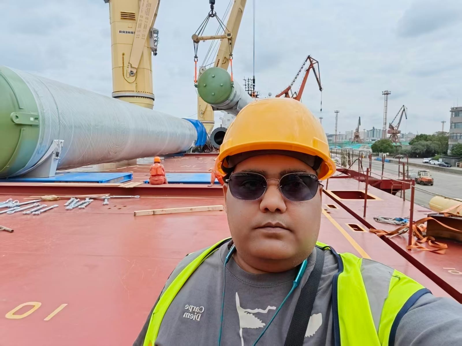Mrinal Sinha on a cargo ship deck at a Chinese port, hard hat and hi-vis vest