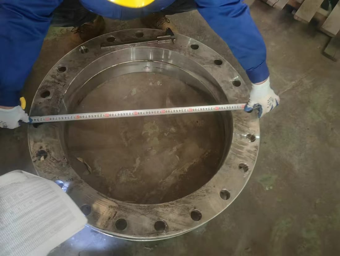 Measuring a fabricated steel flange against the drawing with a tape measure
